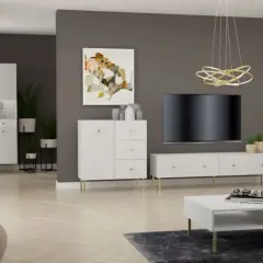 Nowoczesny salon z białymi meblami o prążkowanej fakturze, złotymi detalami i szarą ścianą.