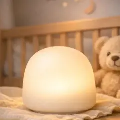 Miękka, biała lampka nocna dla chłopca, która rozświetla pokój. Obok siedzi pluszowy miś, gotowy do snu.