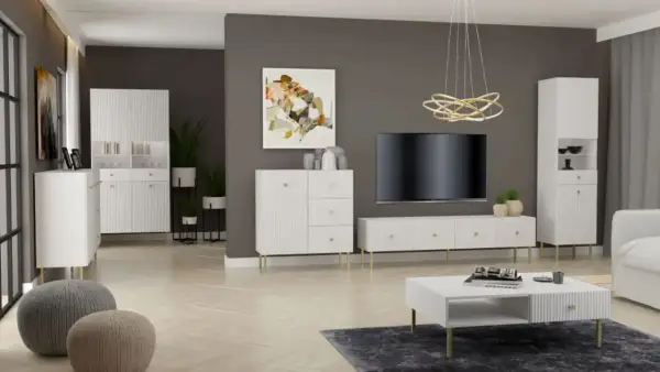 Nowoczesny salon z białymi meblami o prążkowanej fakturze, złotymi detalami i szarą ścianą.